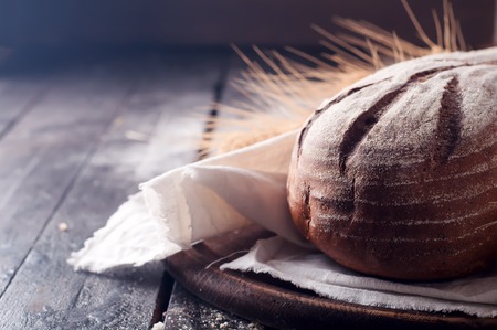 Rustic bread and wheat on dark wood table. Dark moody background with free text space.の写真素材