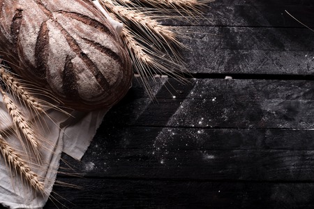 Freshly baked traditional bread on wooden table. Dark moody background with free text space.の写真素材