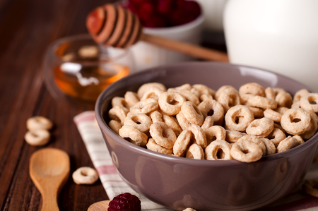 Healthy breakfast - cereal rings in a e bowl with milk, honey, berries on dark backgroundの写真素材
