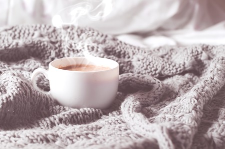 Having a cup of coffee on gray blanket in bed.  toned photoの写真素材