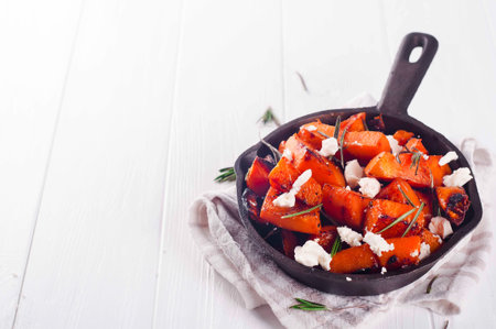 Roasted, baked pumpkin with addition aromatic herbs and goat cheese . Healthy food concept with copy...
