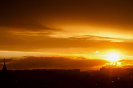 sunset with rainy clouds above the roofs of buildingsの写真素材