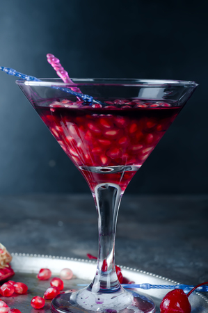 Pomegranate, cut into sections on a metal dish in the background of the shot glasses with red drinkの写真素材