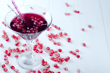 Pomegranate martini with pomegranate seeds in a glass on a white wooden backgroundの写真素材