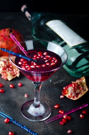 Pomegranate martini with pomegranate seeds in a glass and bottle in the backgroundの写真素材
