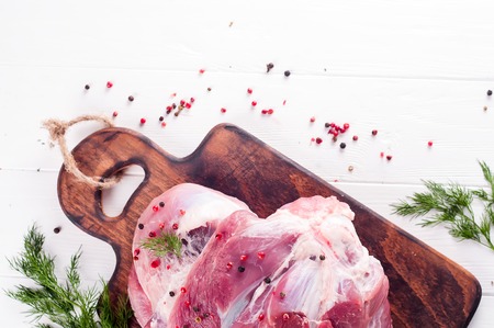 pieces of meat and bunch of parsley and spices on cutting board isolated on white backgroundの写真素材