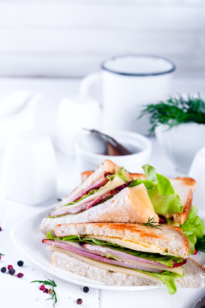 Club sandwich with sausage on a white plate on a white background woodenの写真素材