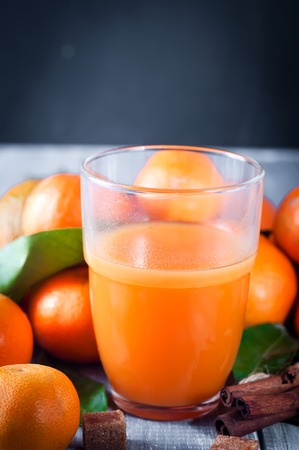 Healthy mandarin juice, cinnamon sticks and tangerines on wooden tableの写真素材