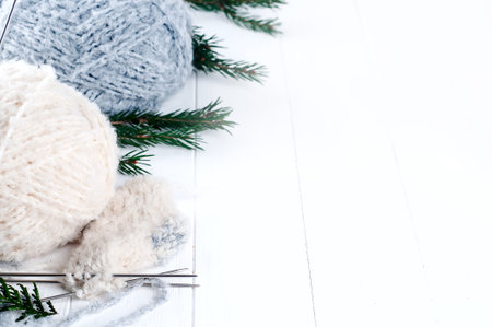 Knitting with a white coat on grey knitting needles on white with green treeの写真素材