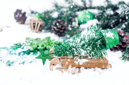 wooden winter sleigh carrying a small Christmas tree on a snow backgroundの写真素材