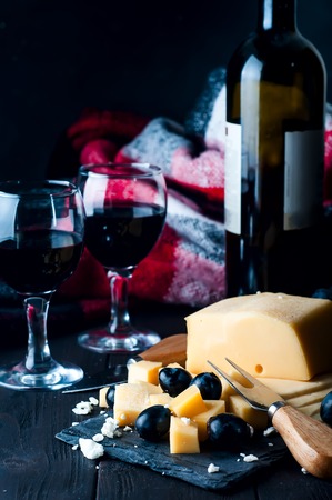 two glasses of red wine, cheese and a warm blanketの写真素材