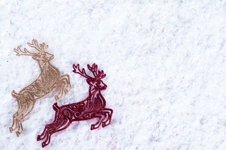 Two decorative deer red and gold colors on the white snowの写真素材