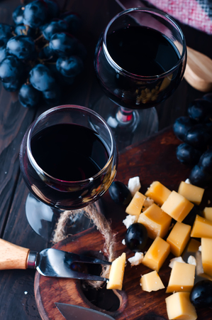 two glasses of red wine, grapes and a warm blanketの写真素材