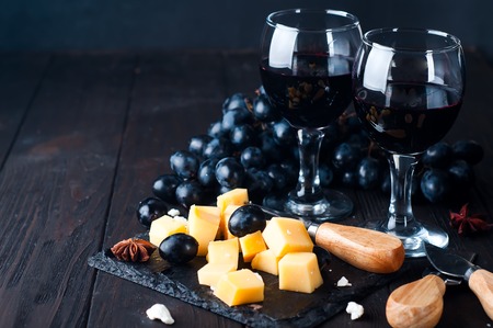 cheese plate on a wooden table with wine on a dark wooden backgroundの写真素材
