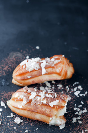 eclairs with almond flakes on a dark concrete background