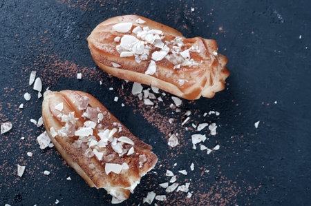 eclairs with almond flakes on a dark concrete background