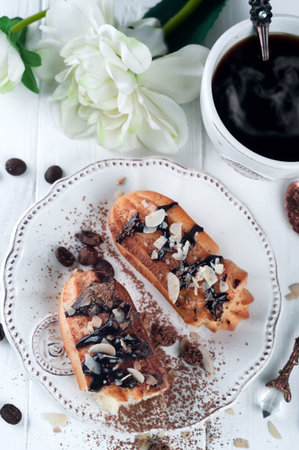 eclairs with cup of coffee and flovers on a white wooden background. Valentines day with breakfast