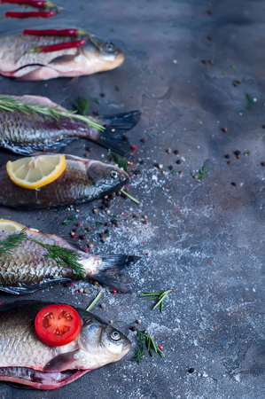 Food background for fish dishes cooking with various ingredients. Raw crucian with oil, herbs and spices on cutting board, top viewの写真素材