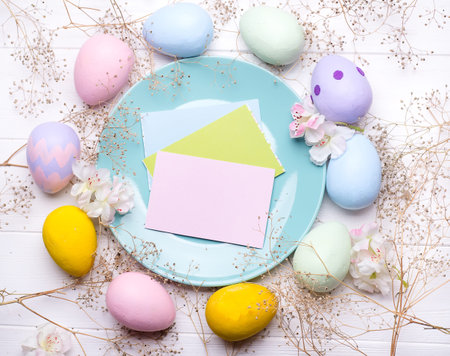 Pastel color easter eggs with a plate on white wooden bacgroung , copy space flat lay
