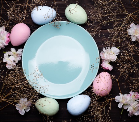 Pastel color easter eggs with a plate on dark wooden bacgroung , copy space flat layの写真素材
