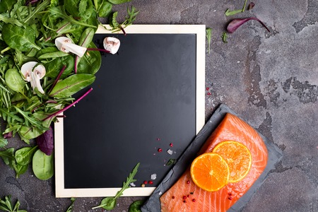 Salmon fillet with fresh salad on a board chalk, flat layr. Healthy food conceptの写真素材