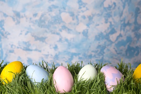 Colorful easter eggs on meadow over stone sky background.の写真素材