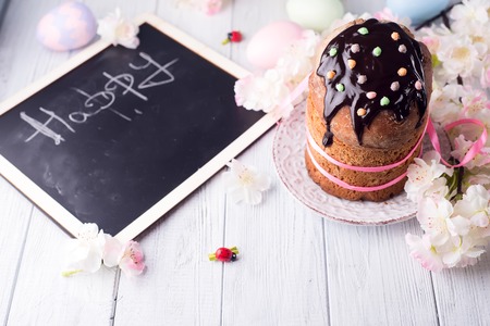 Easter cake with colored eggs and board chalk copy space on a white wooden background, top view flat layの写真素材