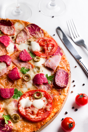 Pizza with sausage and tomatoes and wine on a white backgroundの写真素材