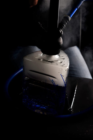 Man smokes hookah. Hookah bowl with tobacco and smoke on black background