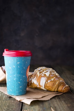 Coffee to go in a paper cup with croissantsの写真素材