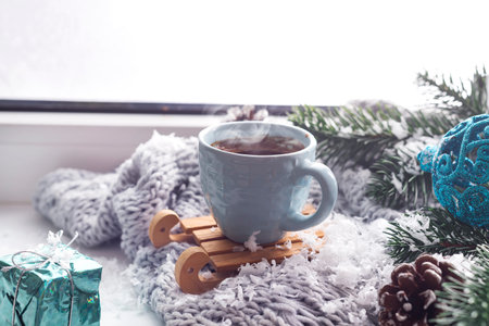 cozy soft gray blanket with a blue cup of coffee on the background of a window decorated with rain drop warming moments winter holidaysの写真素材