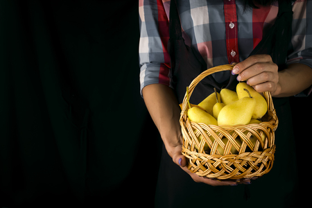 Female hands hold a basket with pearsの写真素材