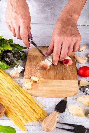 female hands cut prepare ingredients for pasta with mushrooms