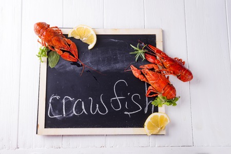 boiled crawfish with fresh lemon on a chalkboard on a white wooden background flat lay copy spaceの写真素材