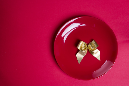 Gold ribbon on red plate isolated on red, flat lay copy space. Valentine's conceptの写真素材