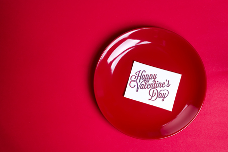 red plate with a card on red background, flat lay copy spaceの写真素材