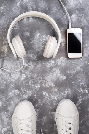 Flat lay Of White Sneakers On stone Background with phone and headphones.の写真素材