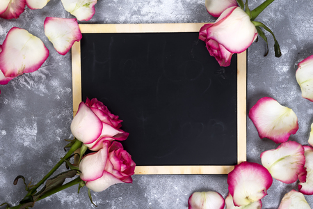 Beautiful rose flowers on gray stone table. Floral border.の写真素材