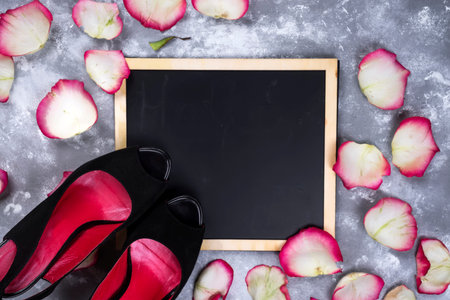 Beautiful rose flowers and woman shoes on gray stone table. Floral border.の写真素材