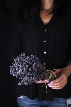 Female florist tying up fresh bouquet with lavender, close-upの写真素材