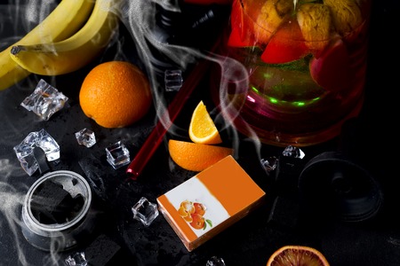 Red hookah with orange and with a box of tobacco and a place for your design on a black backgroundの写真素材