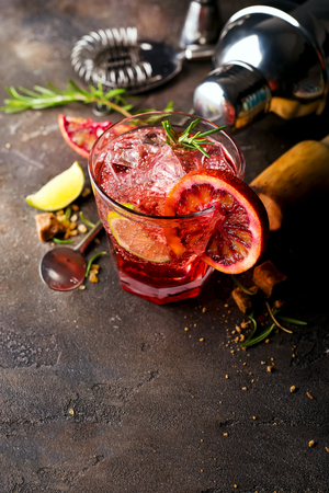 Negroni coctail standing on the stone dark background and served with cubes of brown sugar and Shaker, copy spaceの写真素材