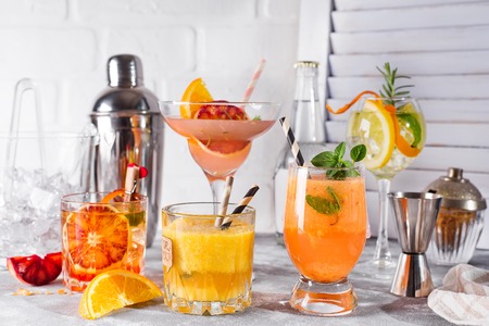 Set of classic cocktails of gin tonic with orange, with lime and mint leaves in glasses on white wooden backgorundの写真素材