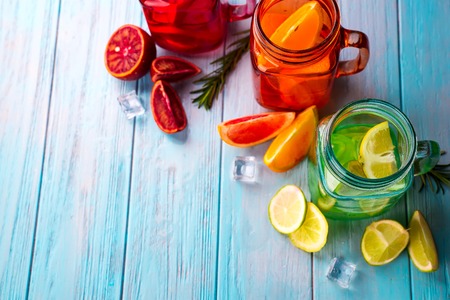 three colored glasses with citrus lemonade and a slice of fruit on a blue backgroundの写真素材