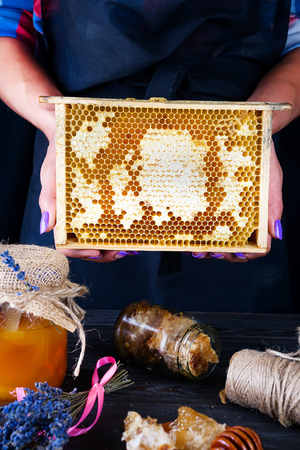 Honey comb with honey. A woman holds honeycomb on a dark background. Healthy Organic Foodの写真素材