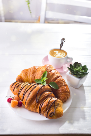 Fresh Croissant with berries and cup of coffee for breakfast, suculent flowers on white wooden stone , copy spaceの写真素材