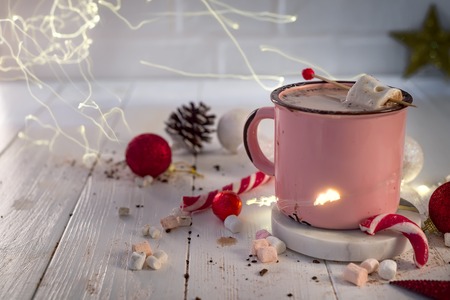 Enamel cup of hot cocoa with mini marshmallows and candy canes with beautiful Christmas lights of bokeh. Christmas conceptの写真素材