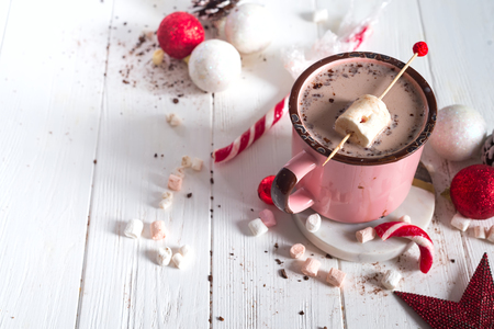 Enamel cup of hot cocoa with mini marshmallows and candy canes with pine and beautiful Christmas toys on white background.の写真素材