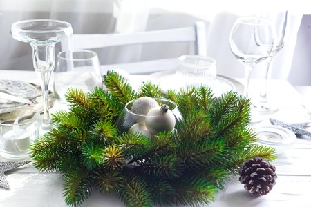 Christmas wreath with toys on the table with Silver Christmas Table Setting with christmas decorations above light window, copy spaceの写真素材