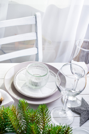 Christmas wreath with toys on the table with Silver Christmas Table Setting with christmas decorations above light window, copy spaceの写真素材